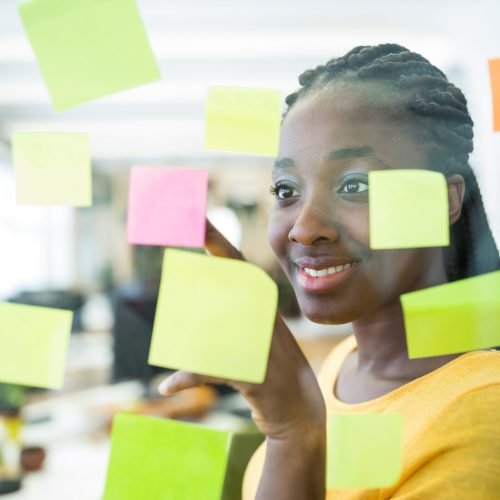 Female graphic designer looking at sticky notes in office