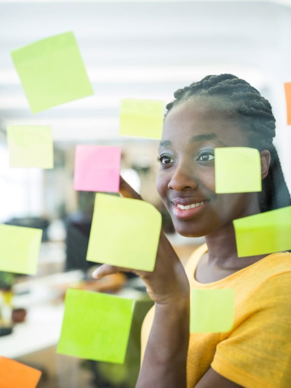 Female graphic designer looking at sticky notes in office